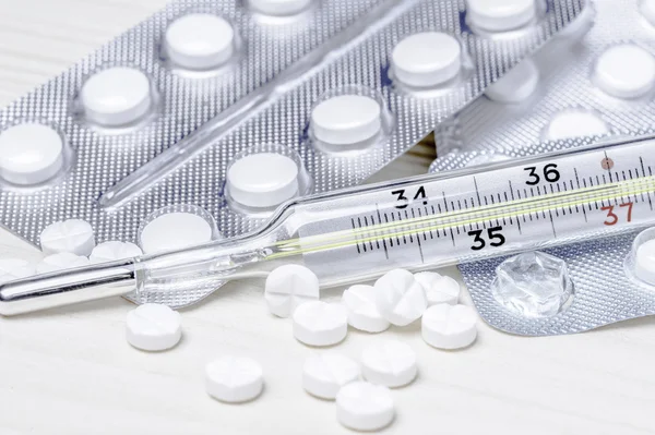 Beyaz tıp tablet blister ve termometre ahşap bir masa üzerinde kapat