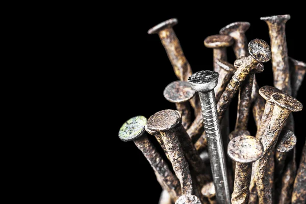 Liderlik kavramı. Yeni çelik çivi grubu üzerinde eski bir siyah arka plan üzerinde çivi pas.