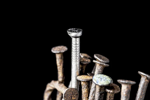The leadership concept. New steel nail over group of old rust nails on a black background. — Stock Photo, Image