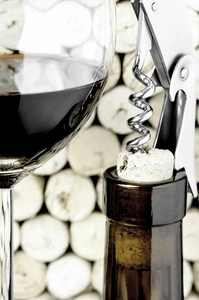 Ein Weinglas, eine Flasche und ein Korkenzieher auf Korkhintergrund im vertikalen Format — Stockfoto