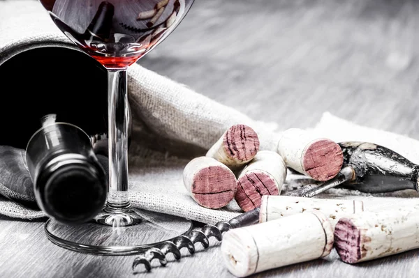 Bicchiere da vino, tappi, cavatappi e bottiglia su fondo di legno con tessuto — Foto Stock
