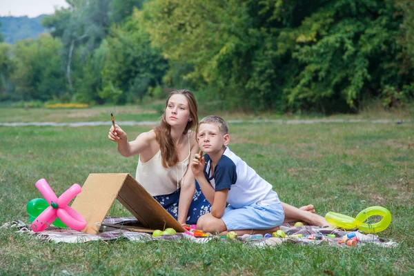 공원에서 페인트를 그녀의 동생을가 르 치 려 하는 누나 — 스톡 사진