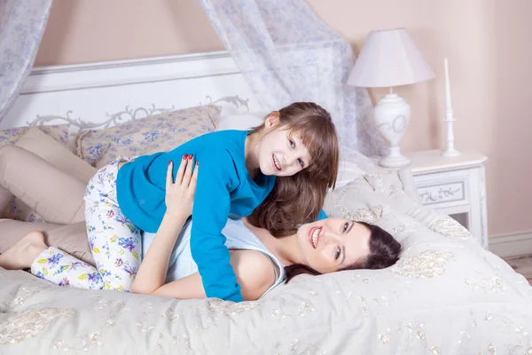 Šťastná matka a dcera ležela v posteli a baví. — Stock fotografie