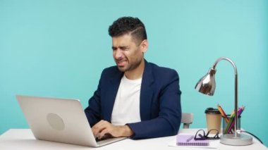 Üzgün bir ofis çalışanı dizüstü bilgisayarla çalışırken yanağına dokunuyor, şiddetli diş ağrısı çekiyor, diş ve diş etleriyle ilgili sorunlar yaşıyor. Mavi arka planda kapalı stüdyo çekimi
