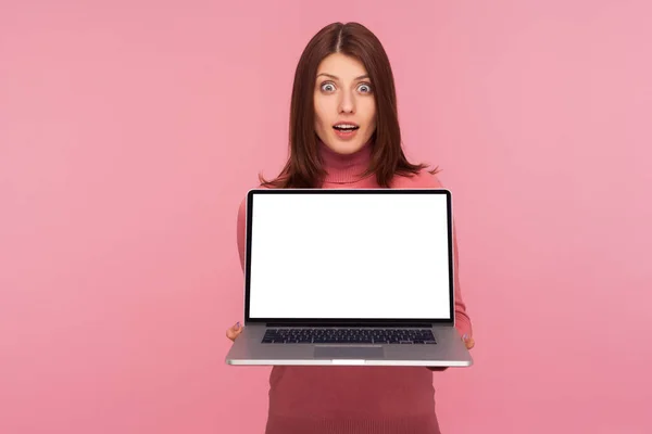 空の画面でラップトップを保持茶色の髪を持つ興奮した幸せな女性は ウェブ広告 商業テキストのためのモックアップ 空白の表示を表示します ピンクの背景に隔離された屋内スタジオショット — ストック写真