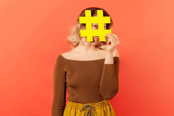 Stijlvolle Vrouw Verbergt Haar Gezicht Achter Grote Gele Hashtag Bord — Stockfoto