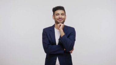 Zarif takım elbiseli mutlu sakallı adam kameraya bakıyor, hayatından memnun, başarılı bir iş adamı. Gri arka planda izole edilmiş kapalı stüdyo görüntüleri