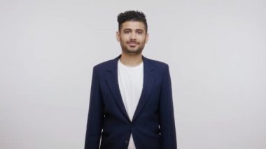 Zarif takım elbiseli iyimser başarılı iş adamının portresi kameraya bakıp gülümsüyor ve hayattan zevk alıyor. Gri arka planda izole edilmiş kapalı stüdyo görüntüleri