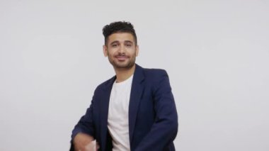 İş elbisesi giymiş, sakallı, göğsünde elleri olan, kameraya özgüvenle bakan, başarılı bir adam. Gri arka planda izole edilmiş kapalı stüdyo görüntüleri