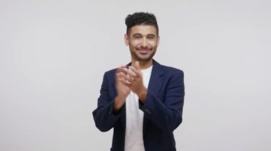 Zarif bir iş elbisesi içinde sakallı, neşeli, olumlu bir adam alkışlayan, performansından memnun olan, bravo. Gri arka planda izole edilmiş kapalı stüdyo görüntüleri