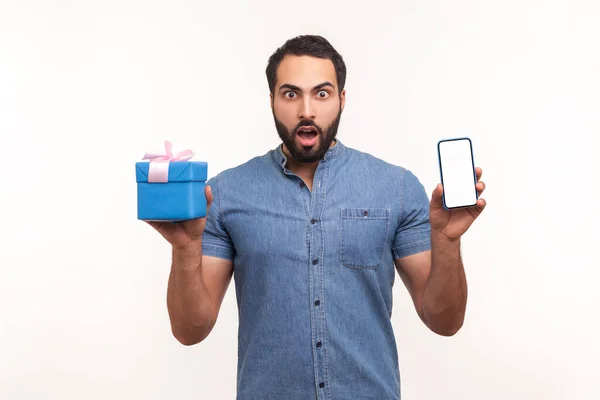 Aufgeregt Überrascht Mann Mit Bart Hält Geschenkbox Und Smartphone Mit — Stockfoto