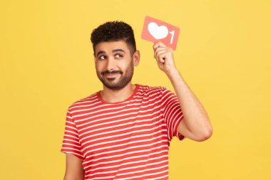 Hayalperest sakallı blogcu başının üstünde kırmızı bir tabela gibi duruyor ve sosyal medyadaki içeriğine daha fazla tepki istiyor. Sarı arka planda kapalı stüdyo çekimleri