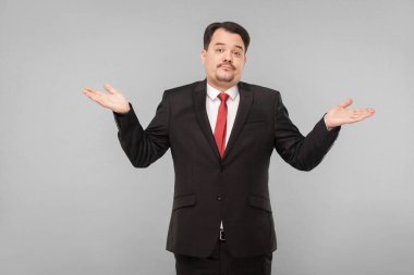 Politikacı ellerini yana açıp sanki rüşvet almamış gibi aptalmış gibi davranır. Stüdyo. Gri arka planda izole. Siyah takım elbiseli ve bıyıklı iş adamı kameraya bakıyor.