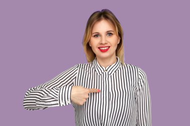 Beni seç, ben kazandım! Kırmızı dudaklı güzel sarışın kadın kameraya heyecanlı bir şekilde gülümsüyor ve güzelliğinden gurur duyuyor. Mor arka planda izole edilmiş kapalı stüdyo çekimi