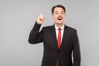 Sonunda çözümü anladım! Dahice bir fikir geldi ve bundan sonra ne yapılması gerektiği çok açık. Stüdyo. Gri arka planda izole. Siyah takım elbiseli, kırmızı kravatlı ve bıyıklı iş adamı kameraya bakıyor.