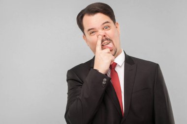 İş yerinde çıldırdı çünkü ambulansta kendinde değil. Kapalı stüdyo çekimi. Gri arka planda izole. Siyah takım elbiseli, kırmızı kravatlı ve bıyıklı yakışıklı işadamı kameraya bakıyor..