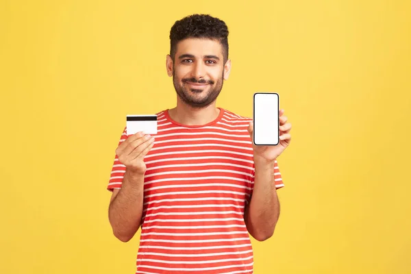 Çizgili Tişörtlü Neşeli Pozitif Sakallı Bir Adam Boş Akıllı Telefon — Stok fotoğraf