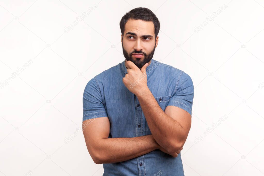 Pensive bearded man holding chin with hand, need to think, planning strategy, thinking over ideas for startup. Indoor studio shot isolated on white background