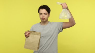 Plastik kötüdür, kağıt iyidir. Plastik torba atan genç bir adam, sadece kese kağıdı kullanmayı öneriyor, onaylıyor, doğru seçim. Sarı arka planda kapalı stüdyo çekimleri