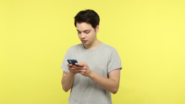 Hombre Adolescente Camiseta Gris Mensajes Texto Teléfono Inteligente Sonriendo Charlando — Vídeo de stock