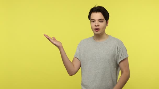 Joyful Young Man Gray Shirt Pointing Aside Showing Advertising Area — Stock Video