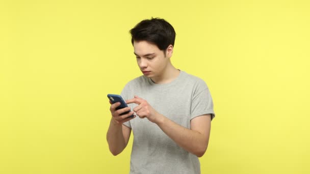 Gündelik Gri Tişörtlü Genç Adam Akıllı Telefonda Web Sayfalarını Kaydırıyor — Stok video