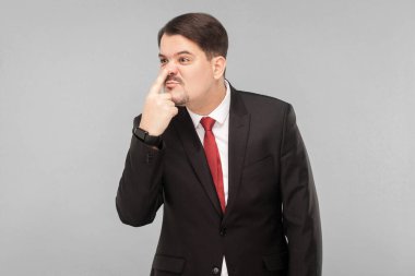 Yalanlarından burnunun bir pinokyo gibi büyüdüğünü anlıyorum. Kapalı stüdyo çekimi. Gri arka planda izole. Siyah takım elbiseli, kırmızı kravatlı ve bıyıklı yakışıklı işadamı başka tarafa bakıyor..