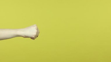 Profil yan görüntüsü, kadın eli boks yumruklarını ele, saldırıya ya da soruna karşı savunmayı gösteriyor. Sarı arka planda kapalı stüdyo çekimleri