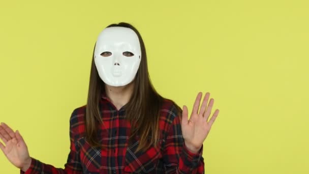 大きな白いマスクで顔をカバーダンスチェックシャツの未知の顔のない女性は 彼女の本当の顔 別の生活を隠して時間を過ごす 黄色の背景に隔離された屋内スタジオショット — ストック動画