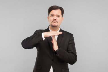 İnsanın daha fazla zamana ihtiyacı var. Üretkenlik olmadan çalışırsan, iş düşer. Kapalı stüdyo çekimi. Gri arka planda izole. Siyah takım elbiseli, kırmızı kravatlı ve bıyıklı yakışıklı işadamı kameraya bakıyor..