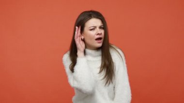 Tüylü beyaz kazaklı meraklı esmer kadın özel konuşmaları dinliyor, gözetliyor, dikkatlice fısıldıyor, sağlık sorunları var. Turuncu arka planda kapalı stüdyo çekimleri