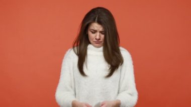 Pofuduk beyaz süveter içinde derinden üzgün bir kadın ağlıyor, umutsuzca peçeteyle gözyaşlarını siliyor, umutsuz bir durumdan, ayrılıktan, kayıptan kaçmanın bir yolunu bulamıyor. Turuncu arka planda kapalı stüdyo çekimleri