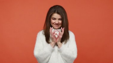 Tüylü beyaz kazaklı kurnaz esmer kadın parmaklarını tıngırdatıyor, entrikalar çeviriyor, entrikalar çeviriyor, eşek şakaları yapıyor, intikam planları yapıyor. Turuncu arka planda kapalı stüdyo çekimleri