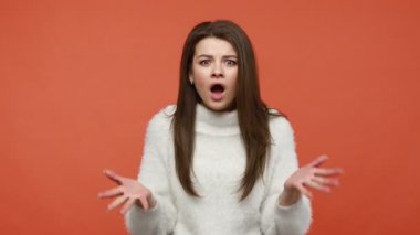 Nasıl yapabildin? Şok olmuş, beyaz kazaklı, kafaya dokunan, kameraya hayretle bakan, aldatmaktan hoşlanmayan mutsuz esmer kadın. Turuncu arka planda kapalı stüdyo çekimleri