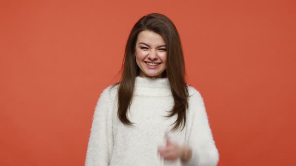 指でジェスチャーのような親指を示すふわふわの白いセーターの非常に幸せな肯定的なブルネットの女性は サービス 勧告に満足しています オレンジの背景に隔離された屋内スタジオショット — ストック動画