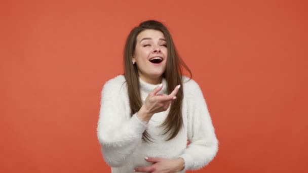 指を指して 大声で笑う白いふわふわのセーターの興奮したショックを受けたブルネットの女性は あなたの成功に驚いて 嘲笑し あなたを嘲笑します オレンジの背景に隔離された屋内スタジオショット — ストック動画