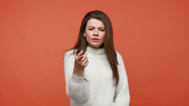 今すぐここでやるんだ 白いセーターの下の指を指示する深刻な女性は すぐに要求し 行動に動機を与える オレンジの背景に隔離された屋内スタジオショット — ストック動画