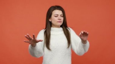 Beyaz pofuduk kazaklı sakin esmer kadın gözlerini kapatıyor ve elleriyle boşluğa dokunuyor. Karanlıkta, görme sorunlarında, körlükte yön bulmaya çalışıyor. Turuncu arka planda kapalı stüdyo çekimleri