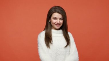 - Gel buraya. Beyaz pofuduk süveter giyen çekici esmer kadın parmaklarıyla işaret ediyor, arıyor, göz kırpıyor kameraya bakıyor ve gülümsüyor. Turuncu arka planda kapalı stüdyo çekimleri