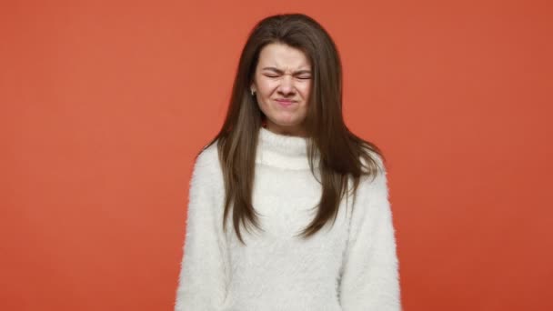 非常に怒っている神経ブルネットの女性は パニック ストレスの多い状況 うつ病で自殺するふりをして 白いふわふわのセーターを作って頭を撃たれました オレンジの背景に隔離された屋内スタジオショット — ストック動画