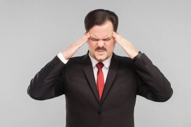 İş yerinde sorunlar, hastalık belirtileri. Kafasını tutan ve migreni olan bir adam. Stüdyo. Gri arka planda izole. Siyah takım elbiseli, kırmızı kravatlı ve bıyıklı yakışıklı bir iş adamı. Kapalı gözler.