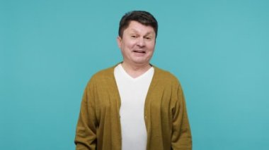 Haha, çok komiksin! Beyaz tişörtlü, hırkalı, heyecanlı orta yaşlı bir adam. Histerik bir şekilde gülüyor, seni işaret ediyor, alay ediyor. Mavi arka planda kapalı stüdyo çekimi