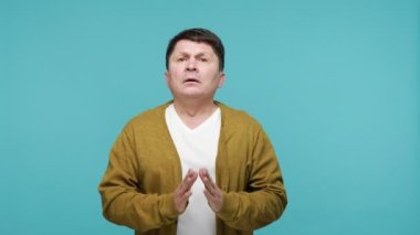 Mutsuz orta yaşlı bir adam gözlerini kapatıyor ve umutsuzca dua ediyor, kafasını kaldırıp tanrıya yalvarıyor, samimi bir şekilde yardım istiyor, özür diliyor ya da yalvarıyor. Mavi arka planda kapalı stüdyo çekimi