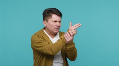 Tişörtlü komik orta yaşlı esmer adam ve silah gibi parmaklarını tutan hırka, kameraya nişan alıp ateş ediyor, silah hareketiyle seçim yapıyor. Mavi arka planda kapalı stüdyo çekimi