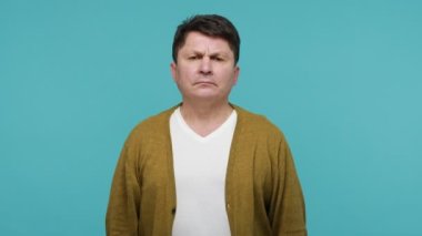 Evet, efendim! Vatansever, orta yaşlı, tişörtlü ve hırkalı bir adam başının yanında el ele tutuşup selam veriyor. Sorumlu bir ifadeyle selam veriyor. Mavi arka planda kapalı stüdyo çekimi