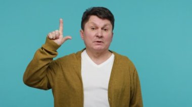 Orta yaşlı tacizci ezik hareketler yapıyor ve seni işaret ediyor, başarısızlıkla suçluyor, saygısızlığını dile getiriyor, başarısızlığınla alay ediyor. Mavi arka planda kapalı stüdyo çekimi