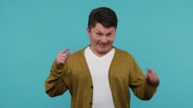 Olgun, koyu saçlı bir adam, aşağıdaki reklam alanını gösteriyor ve gülümsüyor. Promosyon bilgileriniz ve içeriğiniz için. Mavi arka planda kapalı stüdyo çekimi