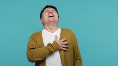 Kalp sorunları var. Depresif, sağlıksız, olgun bir adam göğsünde ani bir ağrı, kalp krizi, miyokardiyal enfarktüs, acil durum. Mavi arka planda kapalı stüdyo çekimi