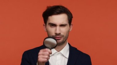 Sakallı iş adamının portresi büyüteçle görüyor, küçük, büyük adam gözü, Louise 'i kullanan komik bir erkek dedektif arıyor. Turuncu arka planda kapalı stüdyo çekimleri