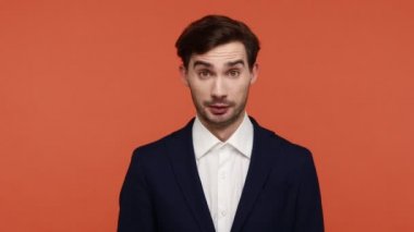 Hey sen! Şok olmuş gözleriyle kamerayı işaret eden, takım elbiseli, esmer, sakallı adamın inanılmaz bir ifadesi var, seni seçiyor. Turuncu arka planda kapalı stüdyo çekimleri.